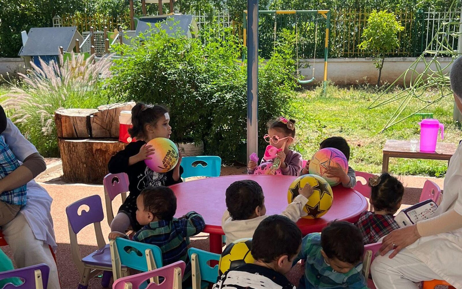Kinderen spelen samen buiten aan tafel bij een project van Stichting Tisier